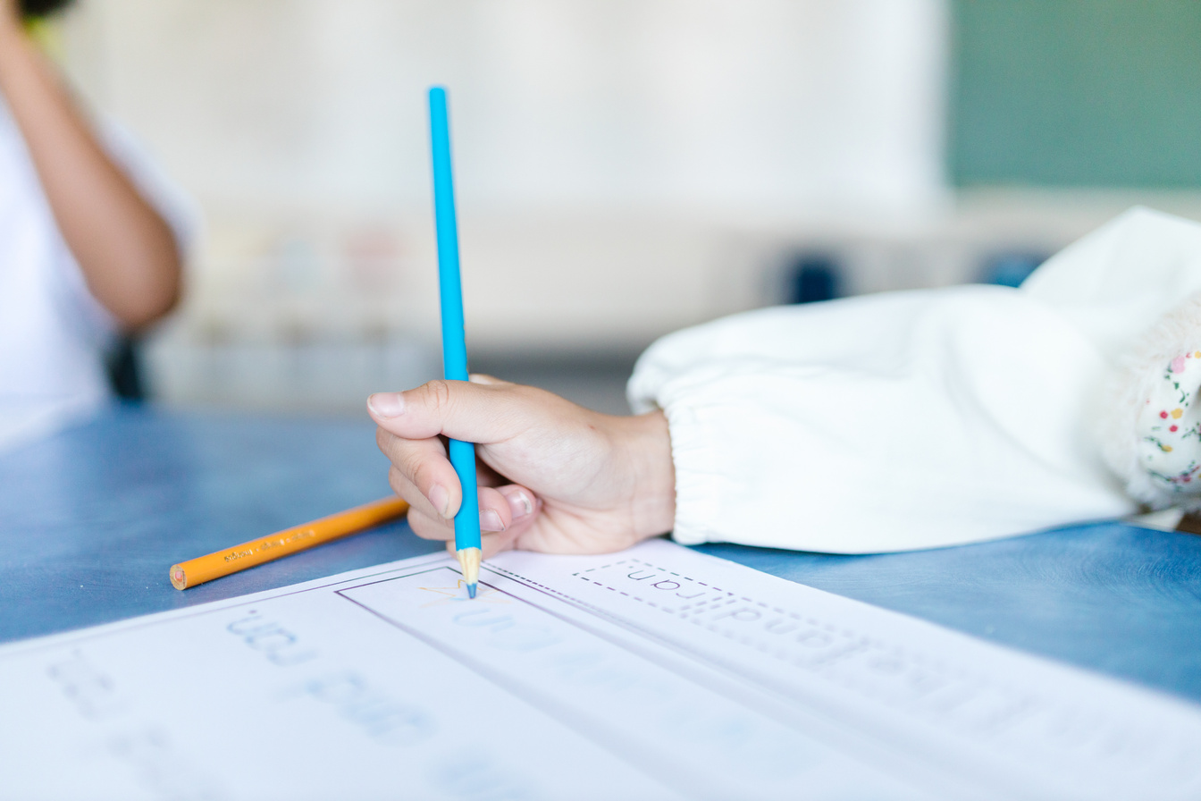 A Kid Writing with a Blue Pencil