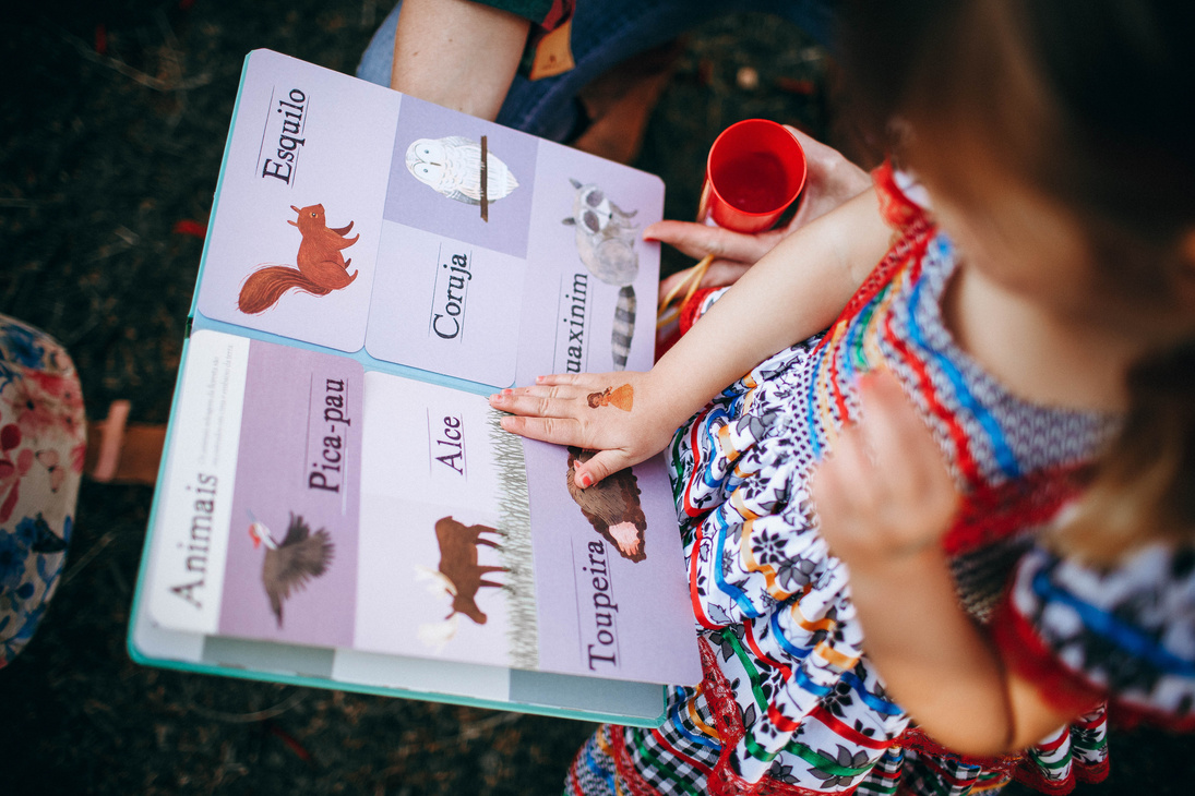 Child reading book with mother in garden